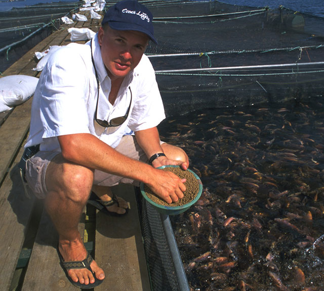 man on dock feeding tilapia cargill aquaculture aquafeed feed