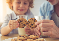Kid enjoying a chocolate chip cookie with a glass of milk 