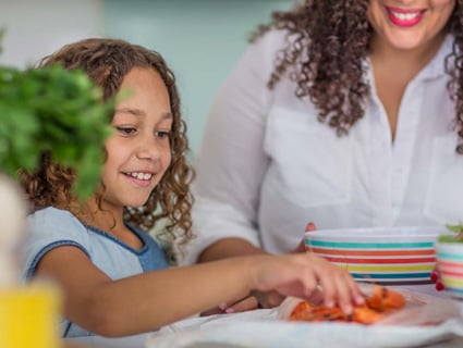 Girl reaching for seafood on a plate with woman smiling