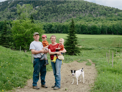father mother two children and a dog with green trees and hill in the background