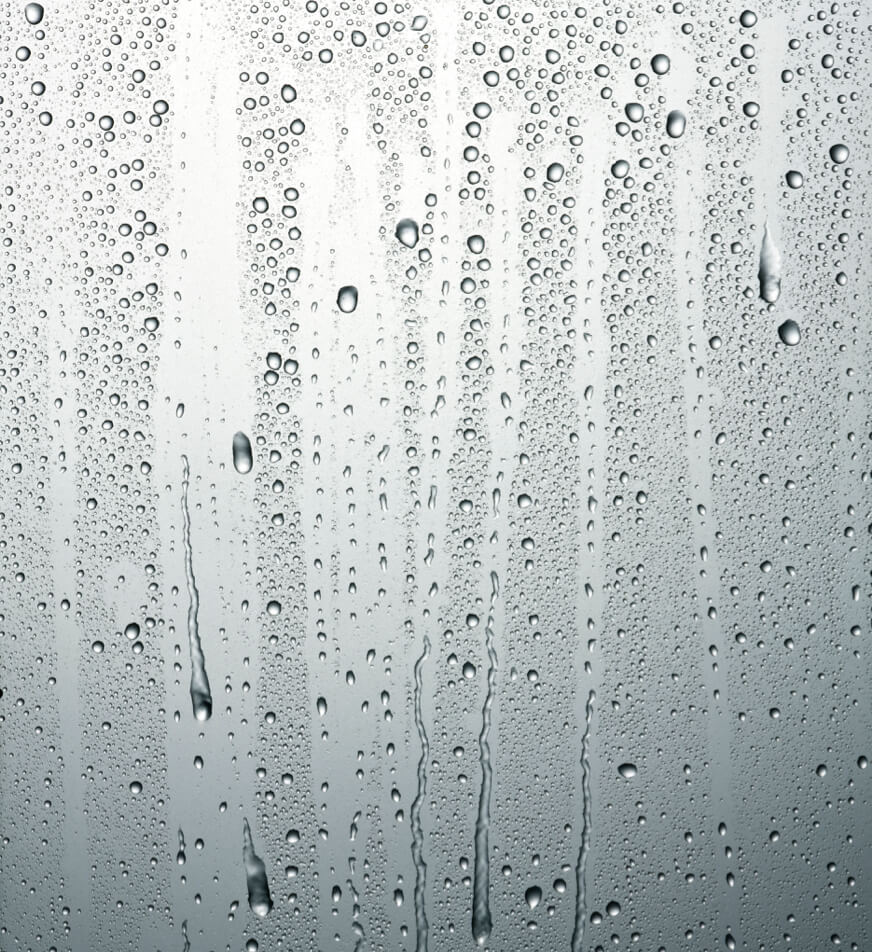 Raindrops dripping down a smooth surface.