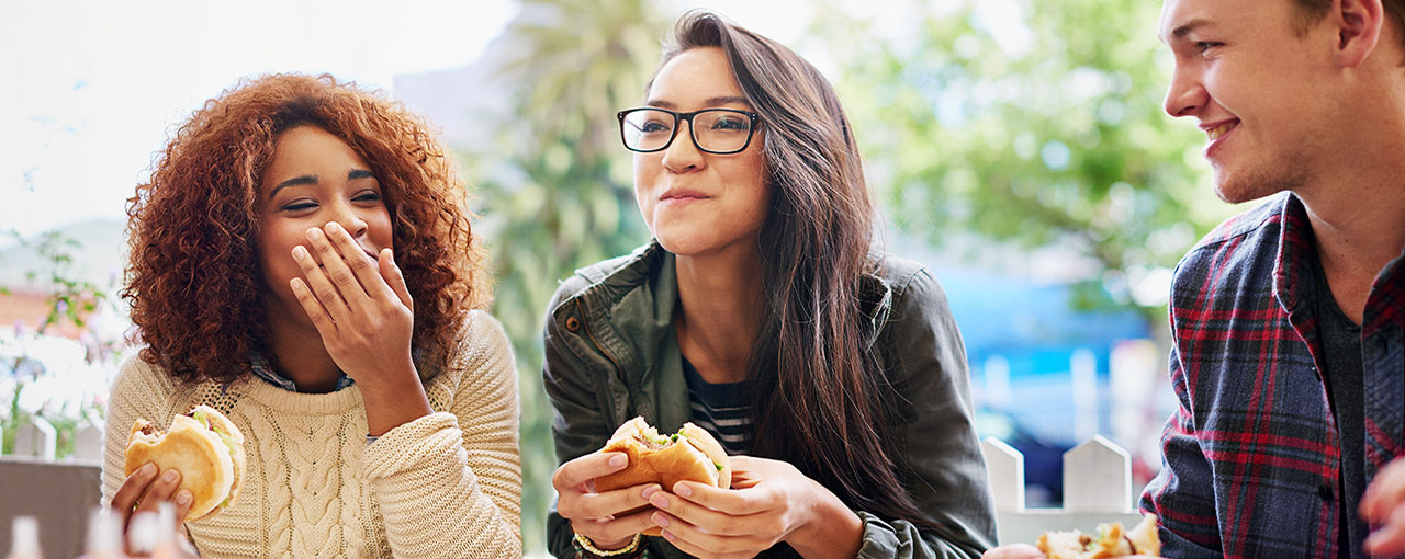 Happy students talking while having lunch break at cafeteria