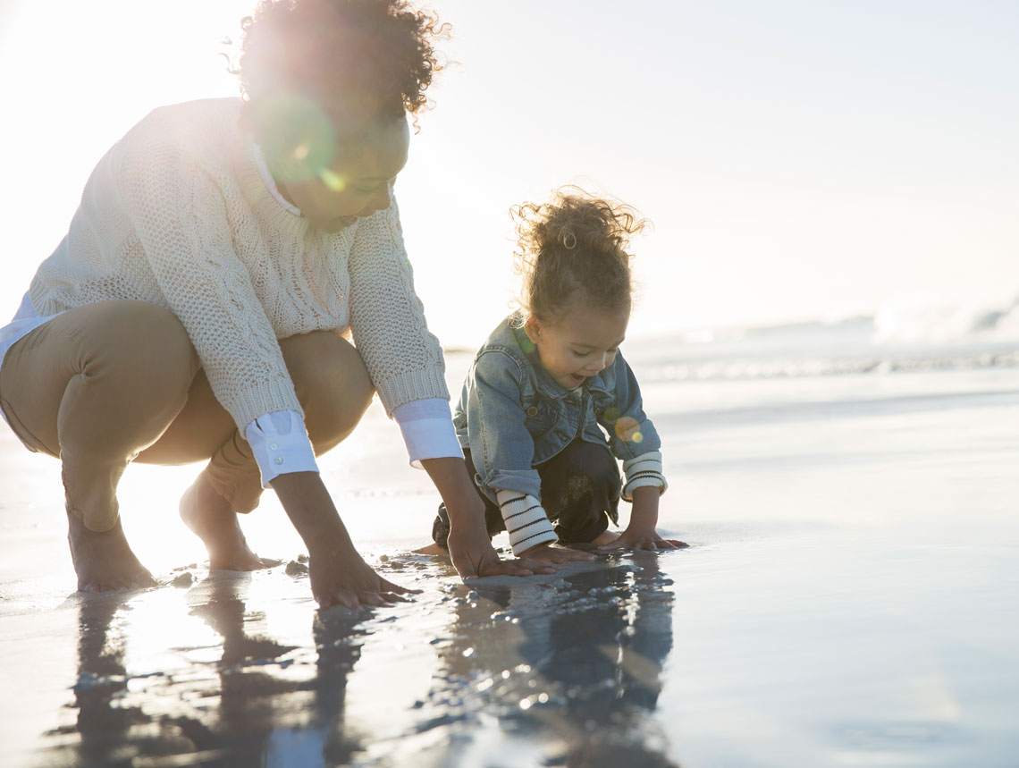 woman and child playing with clean ocean water