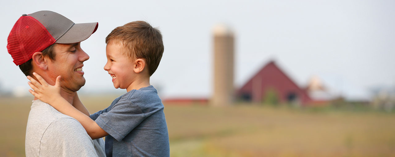 Man Holding Boy in a Field