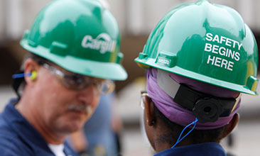 people with Cargill hardhats on. Safety begins here written on them image