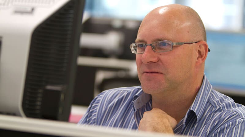 A man looks at a computer screen in an office setting. A man looks at a computer screen in an office setting.