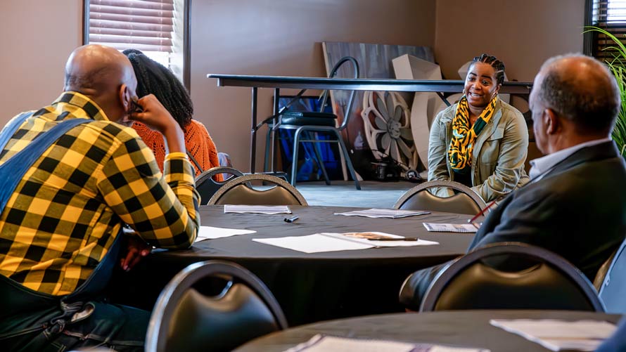 Two farmers listen during a meeting with the leader of a nonprofit organization.