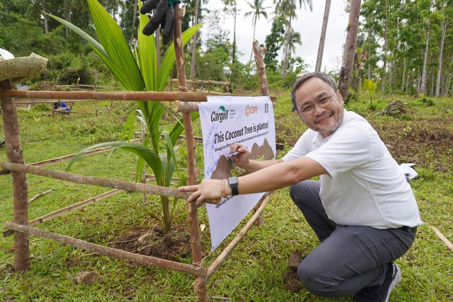 Cargill’s Jonathan Sumpaico signs the tree guard post that protects the coconut he planted at the planting ceremony.