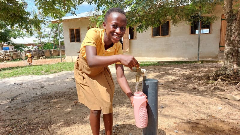 Obaa, a 12-year-old girl in Ghana, filling a bottle with water