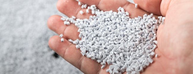 White plastic pellets held in a hand
