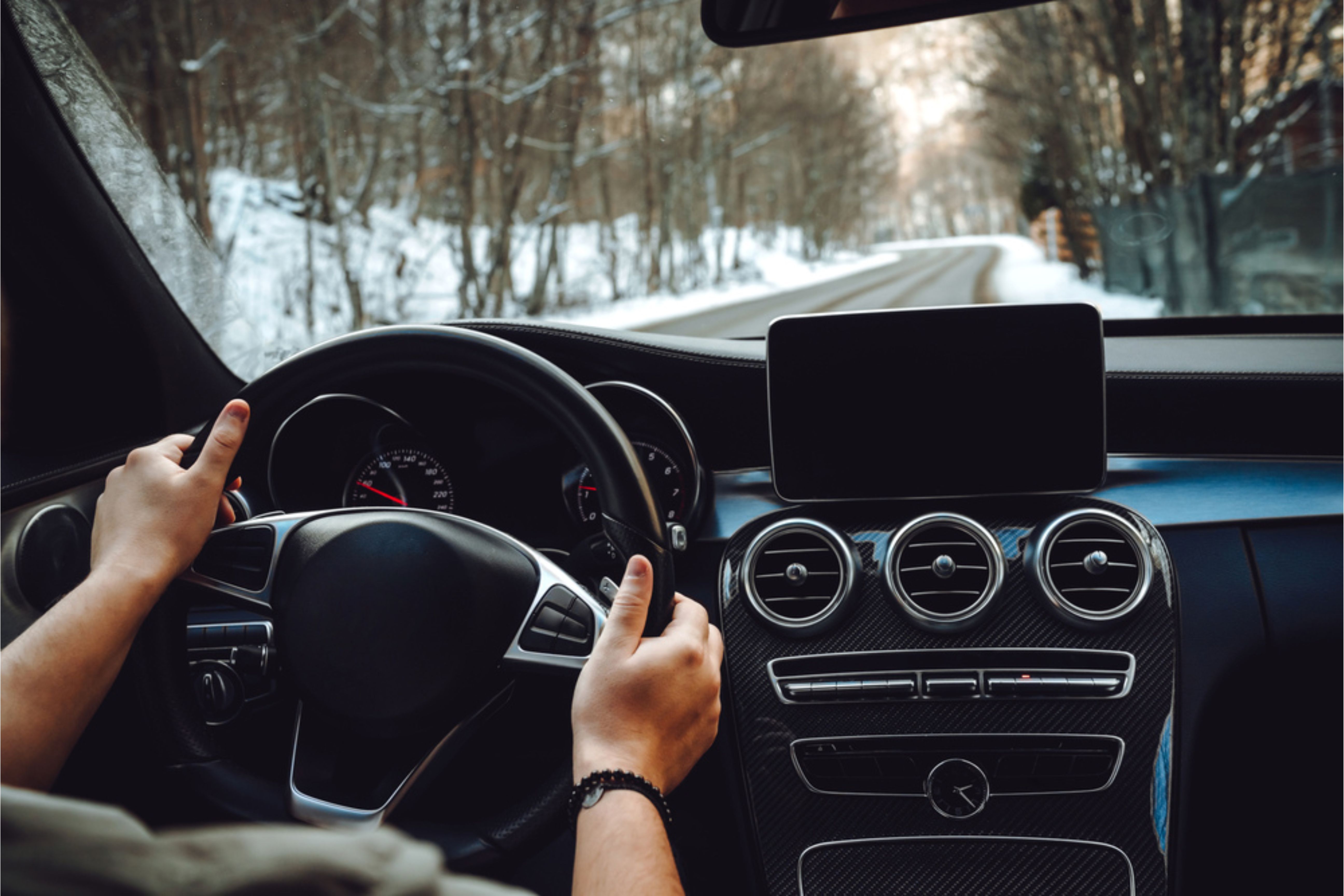 Person with hands on steering wheel and interior of car.