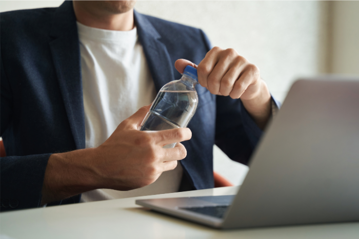 Person in blazer opening water bottle