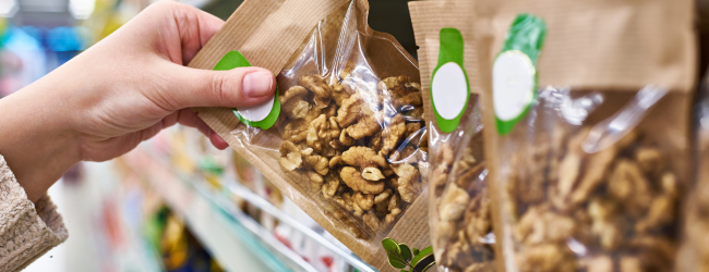 Person grabbing bag of walnuts with clear plastic front packaging