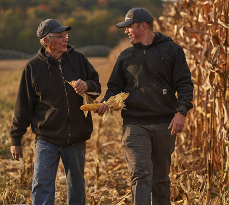 Multigenerational farmers walking next to crops image