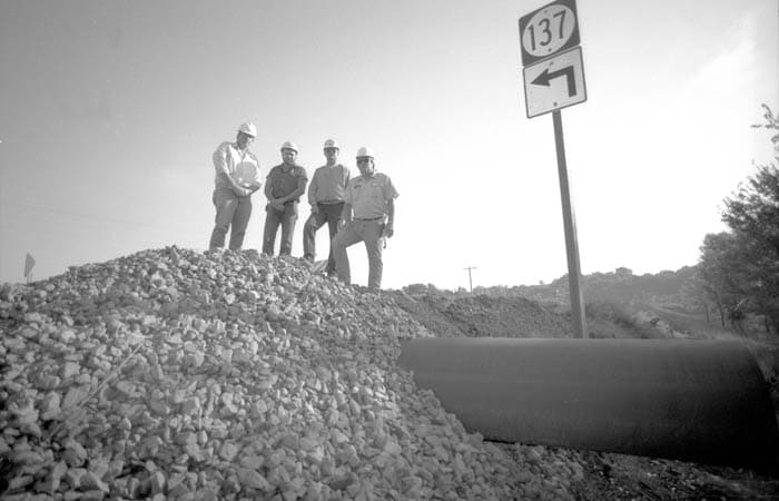 Group of engineers standing on top of a culvert on Highway 137 in Iowa.