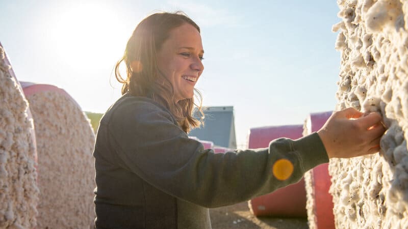 A woman grabs for a piece of cotton on a farm.