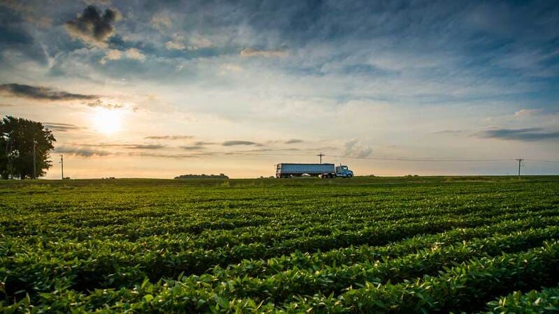 A truck drives on a highway near farmland. A truck drives on a highway near farmland.