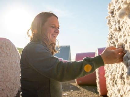 A woman grabs for a piece of cotton on a farm.
