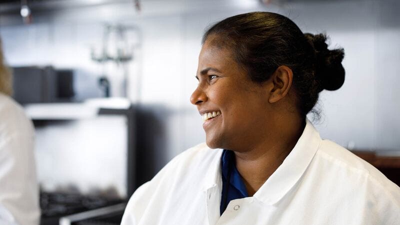 A woman food scientist smiles in a kitchen. A woman food scientist smiles in a kitchen.