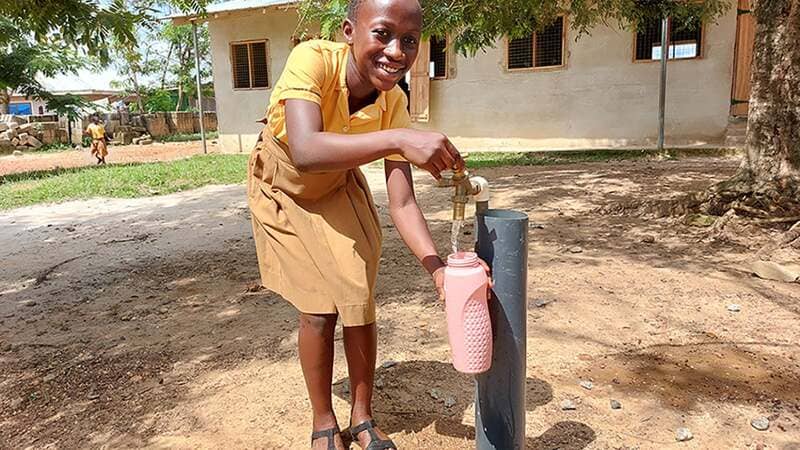 A young girl uses a well to fill her water container.