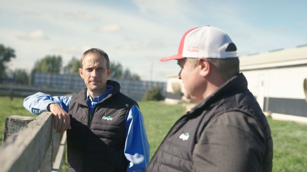 A animal nutrition sales rep talks with a pork producer on his farm.