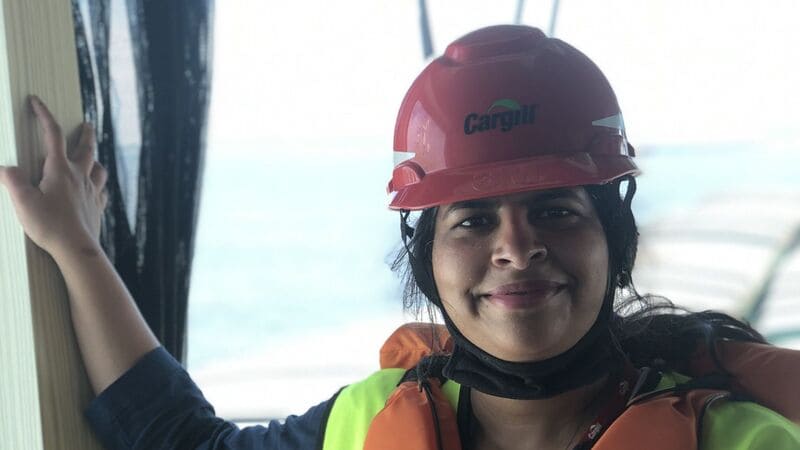  woman smiles while wearing a red hard hat with Cargill written on it.