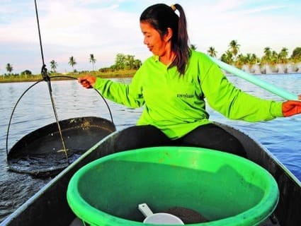 A woman in a boat with a fishing rod and net. 