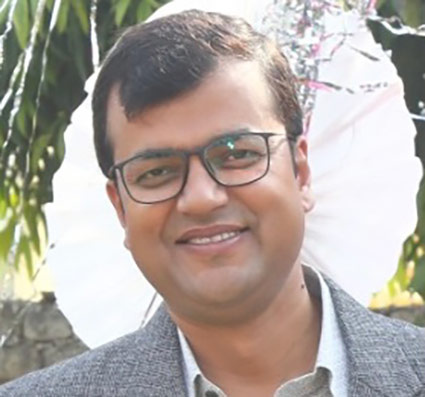 A man wearing glasses smiles. 