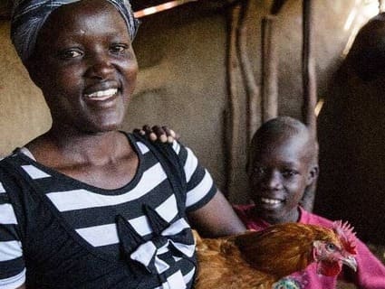 Woman and child posing with a chicken.