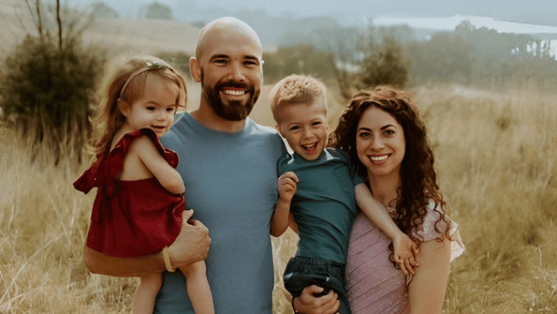 Bethany May, her husband and her two children post for a photo outdoors.