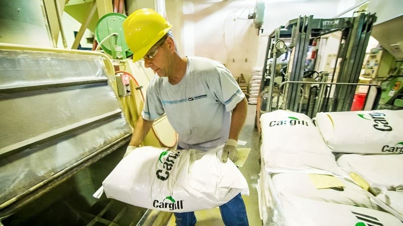 A farmer moves a bag of Cargill animal feed. A farmer moves a bag of Cargill animal feed.