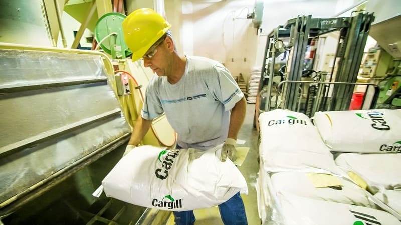 A farmer moves a bag of Cargill animal feed. 