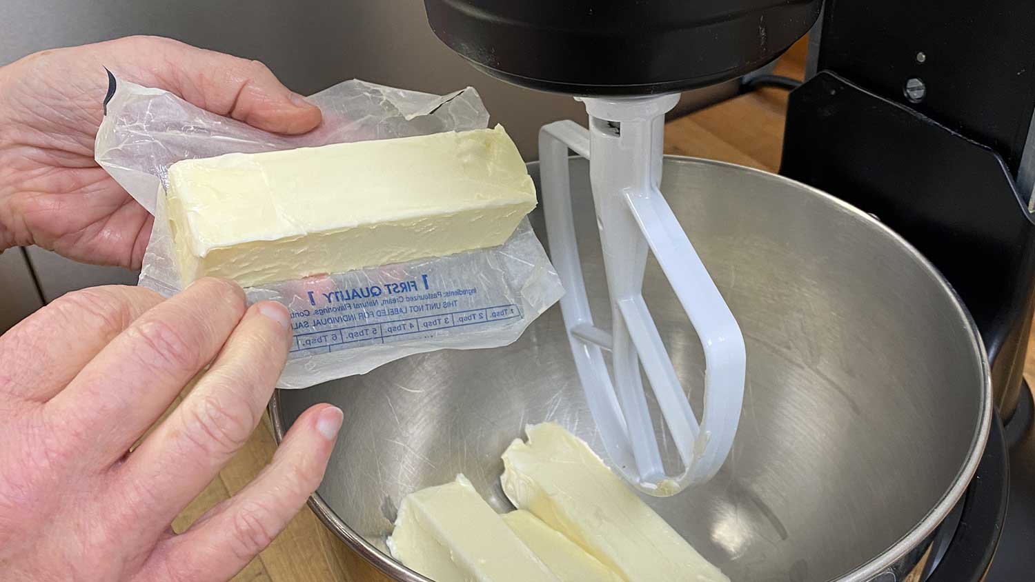 A chef unwrapping butter into a mixing bowl. A chef unwrapping butter into a mixing bowl.