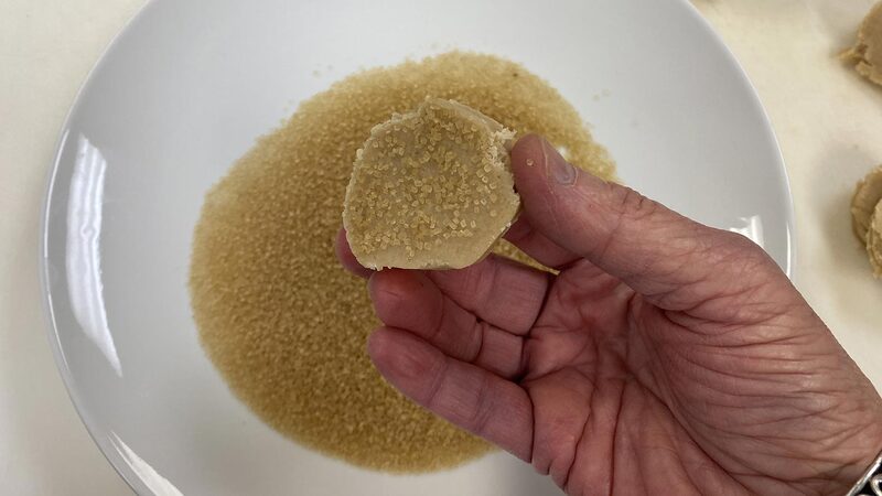 Shortbread dough being dipped into sugar.