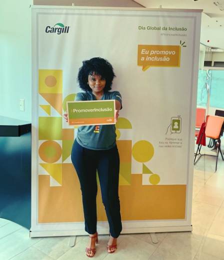 A Cargill employee standing in front of a poster board holding a sign.