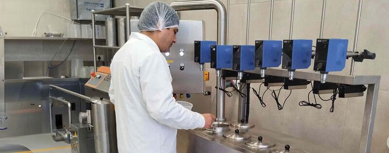 A food scientist in a white lab coat works with a machine in a lab. A food scientist in a white lab coat works with a machine in a lab.