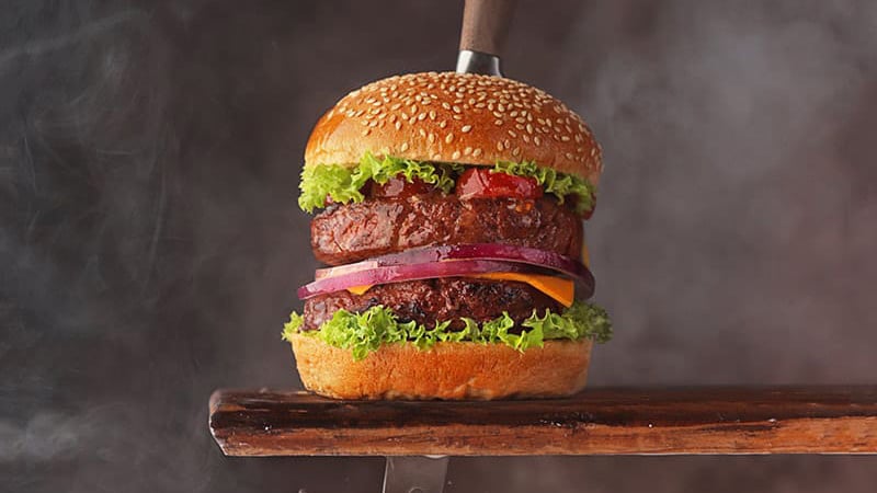 A knife cutting through a thick plant-based burger