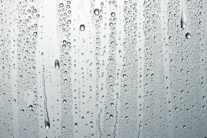 Raindrops dripping down a smooth surface