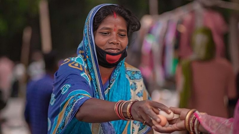 A woman handing over chicken eggs. 