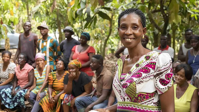 A female cocoa farmer standing with a group of women smiling.