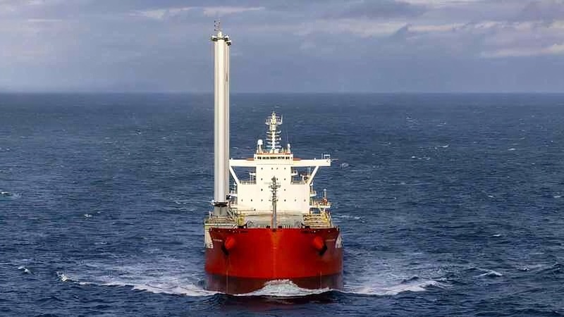 A bulk-carrying ship sailing across the ocean with two giant wing-style sails on display. 