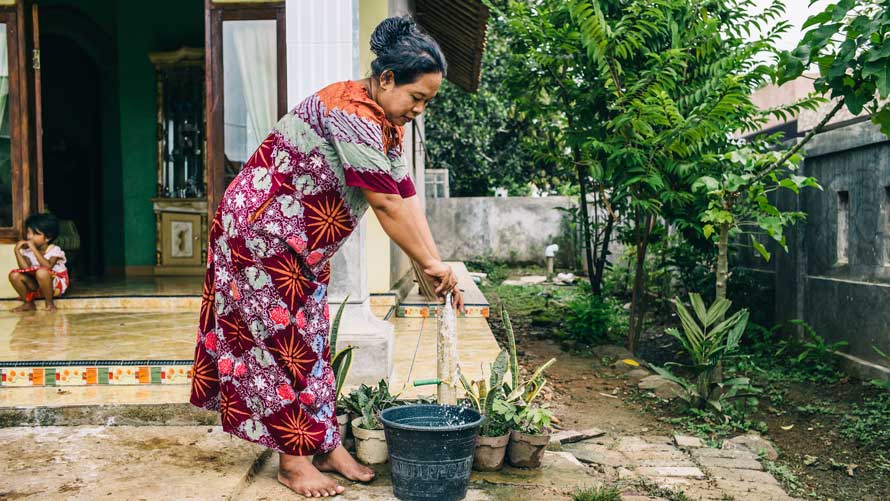 A woman fills a vessel with water. A woman fills a vessel with water.