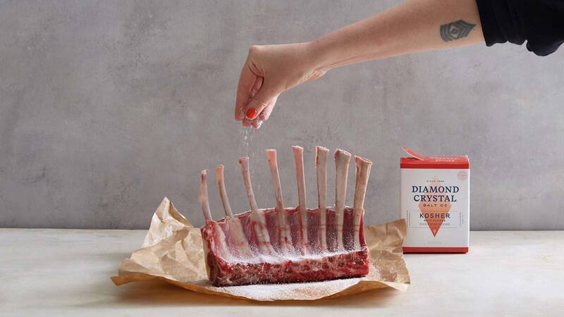A person sprinkles Diamond Crystal Kosher Salt over a rack of ribs.
