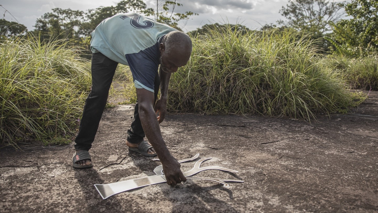 A male cocoa farmer lays down the paper cutout of a tree to signify where it could be planted. 