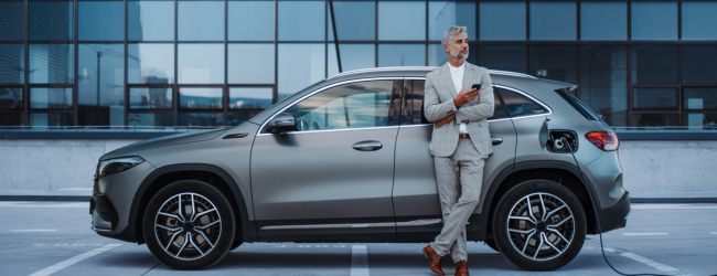 Man leaning on electric car plugged in