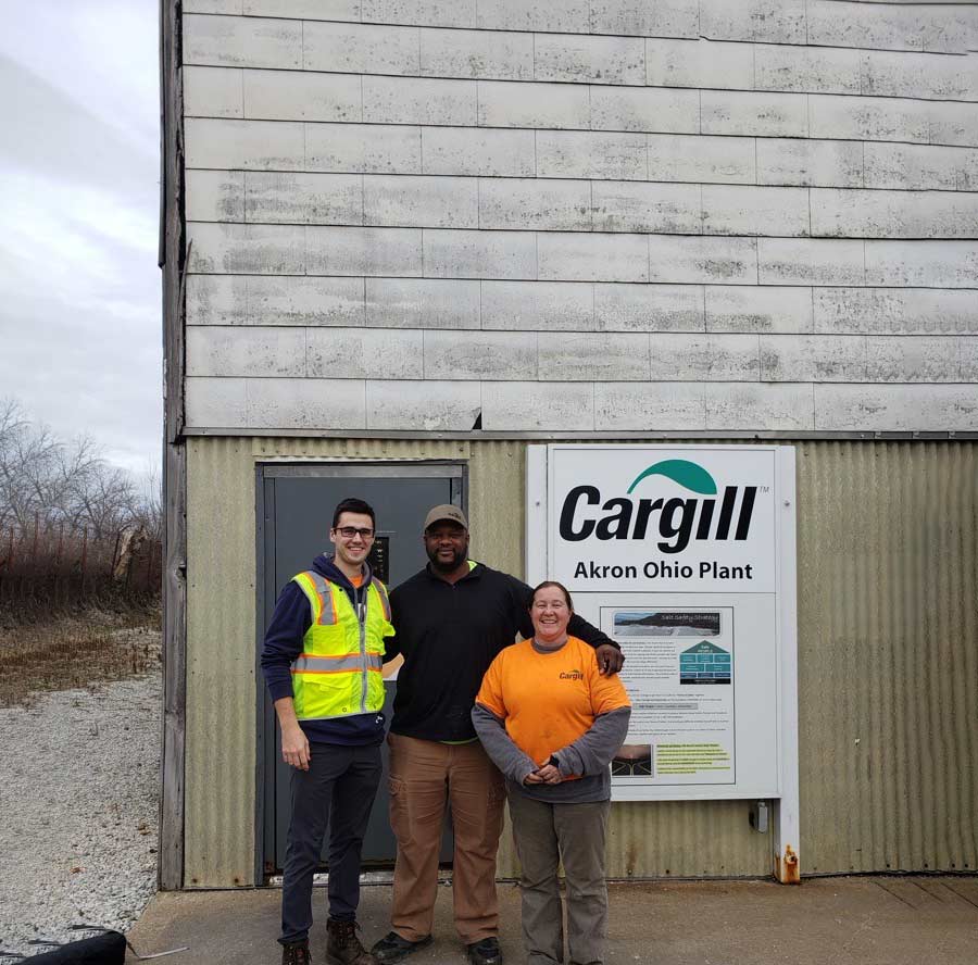 Three plant employees standing in front of a salt facility. Three plant employees standing in front of a salt facility.