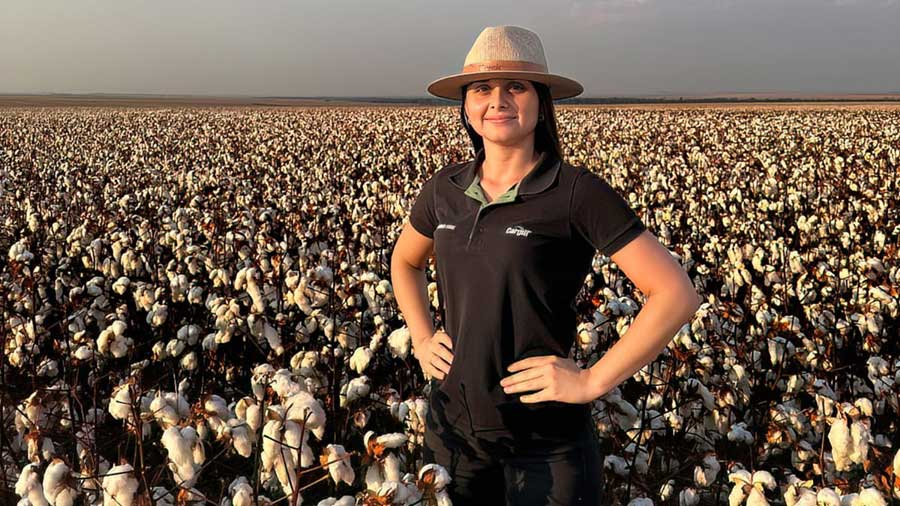 A woman wearing a black Cargill shirt stands in a field of cotton. A woman wearing a black Cargill shirt stands in a field of cotton.