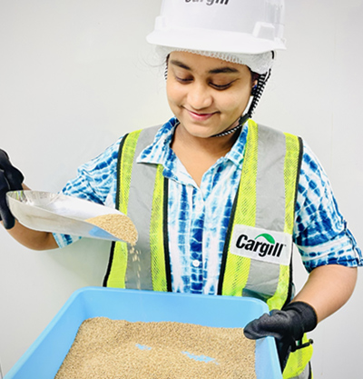 A woman scoops aqua feed out of a basket.