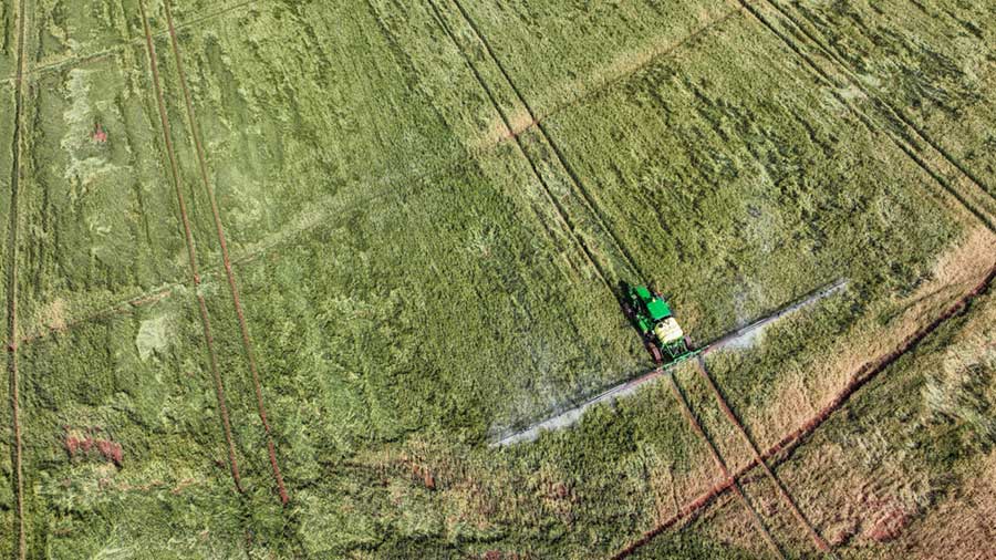 An aerial view of a tractor irrigating a field. An aerial view of a tractor irrigating a field.
