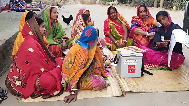 A group of Indian women sitting and listening to a teacher.